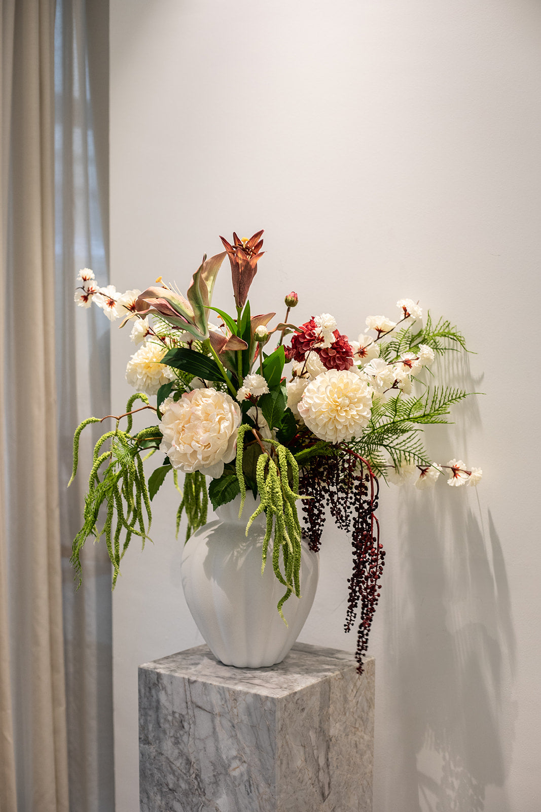 Kunstige blomster sammensat til en buket. Buketten er stylet i Penelope vase i large i farven off-white.
Buketten indeholder
1 x White Hydrangea
2 x Creme Dahlia
3 x Green Fern branch
2 x White Cherry Blossom
3 x Green hanging branch 2
1 x Sunset Dahlia
1 x Creme Peony
1 x Burgundy Berry branch
1 x Burgundy Lily branch