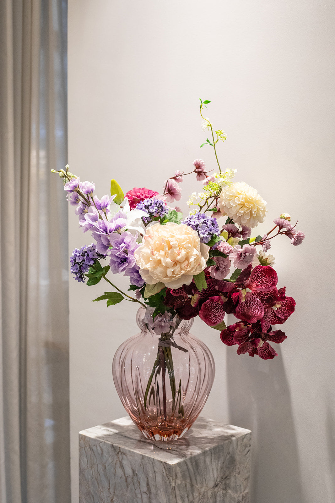 Kunstige blomster sammensat til en buket. Buketten er stylet i Audrey i farven blossom i large.
Buketten indeholder:
1 x Purple Cherry Blossom branch
1 x White Fontanesia
1 x Pink Dahlia
1 x Creme Dahlia
1 x Creme Peony
1 x Light Purple Consolida
1 x White Lily small
1 x White Anthurium
1 x Plum Orchid (7 heads)
1 x Purple Hydrangea branch