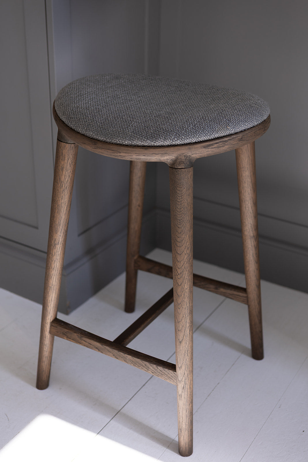 Nohr barstol fra Specktrum i brunolieret egetræ med grå tekstil som sæde.