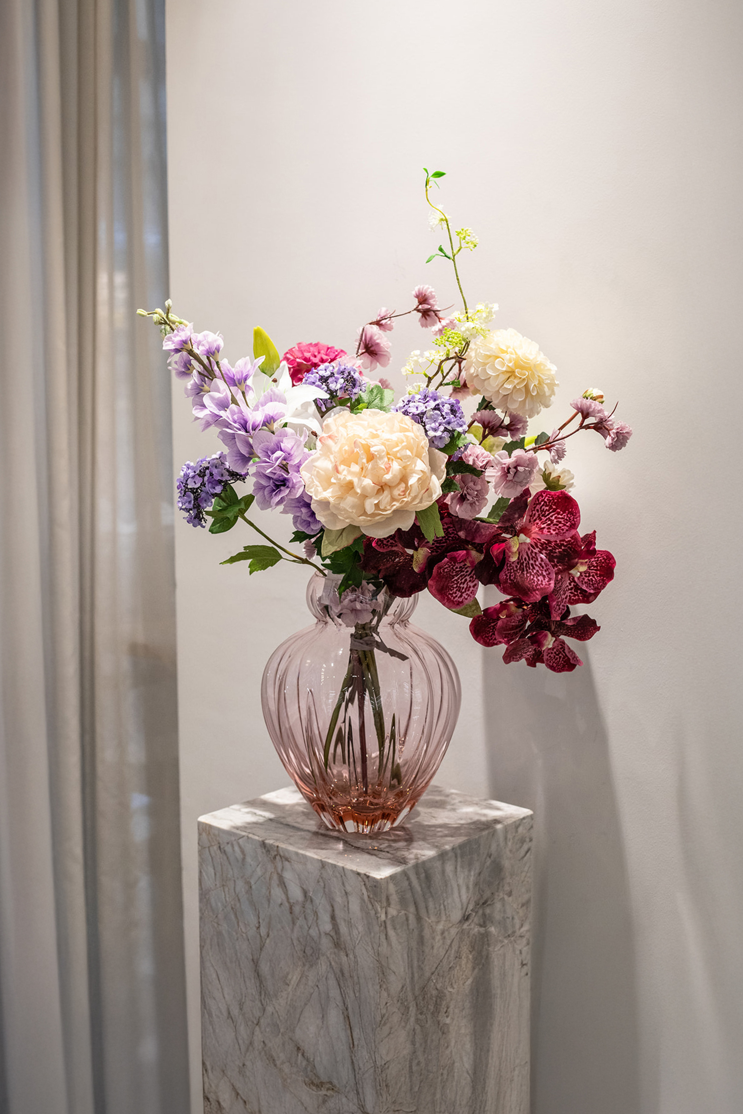 Kunstige blomster sammensat til buket. Buketten er stylet i Audrey i farven blossom i large.
Buketten indeholder:
1 x Purple Cherry Blossom branch
1 x White Fontanesia
1 x Pink Dahlia
1 x Creme Dahlia
1 x Creme Peony
1 x Light Purple Consolida
1 x White Lily small
1 x White Anthurium
1 x Plum Orchid (7 heads)
1 x Purple Hydrangea branch