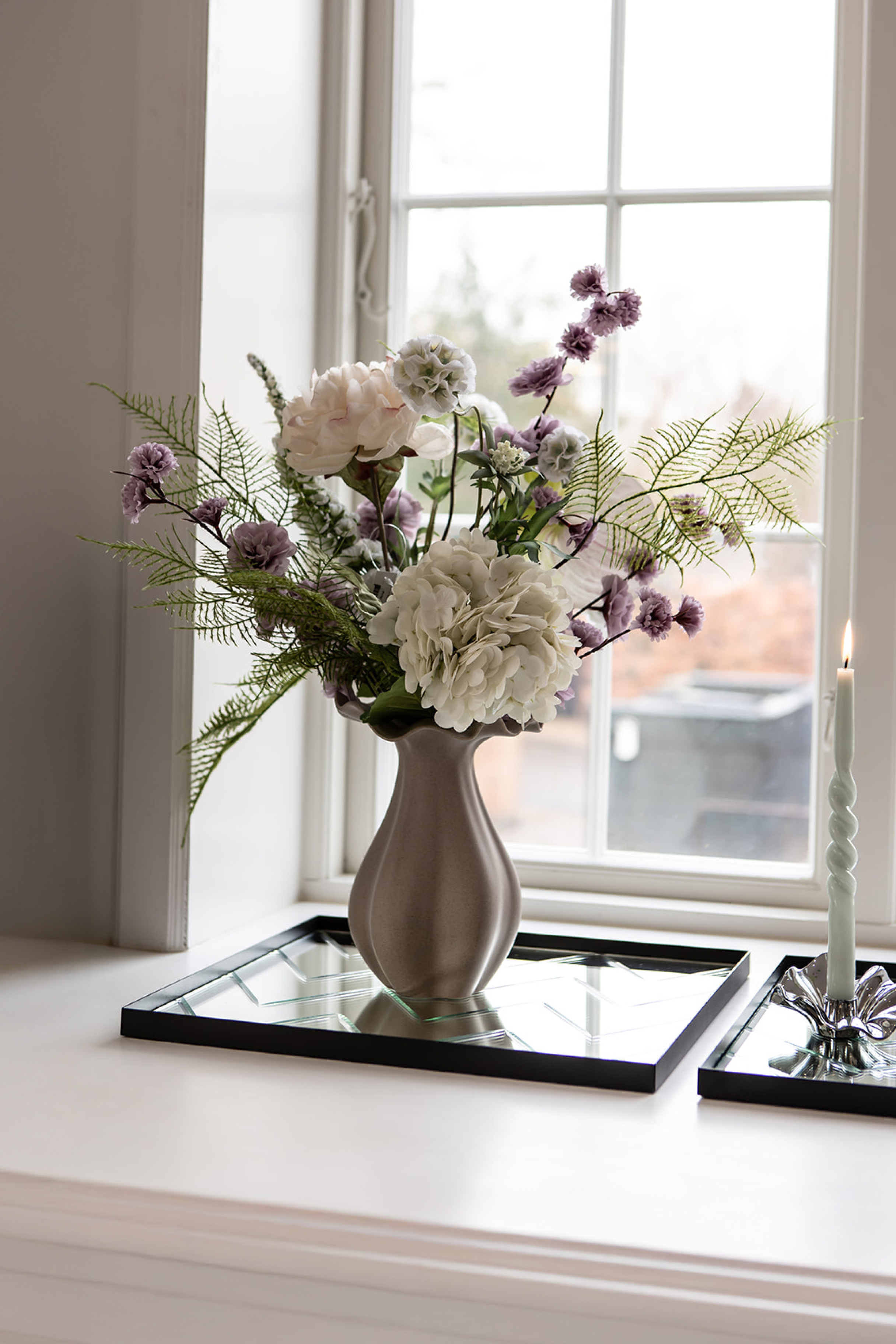 naturtro kunstige blomster fra specktrum placeret i vindueskarm med spejl bakke