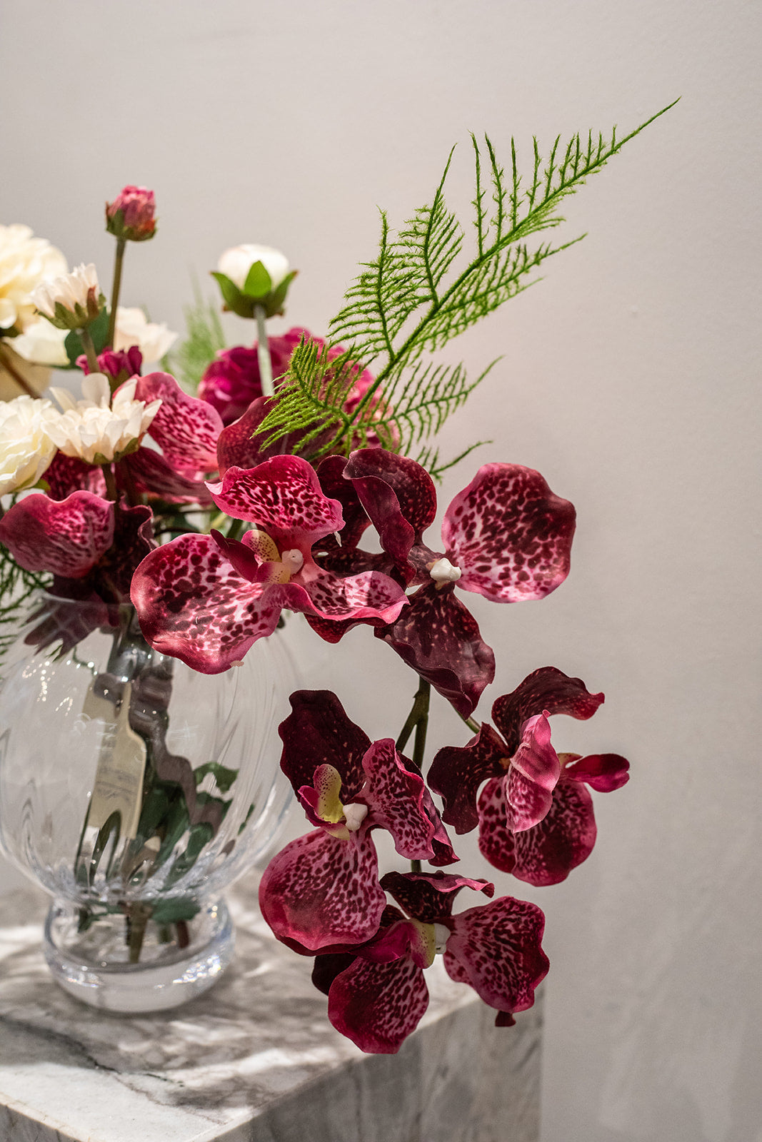 Kunstig buket Stjernestrøet Flor med orkidé i blommefarve, cremefarvet og pink dahlia, hvid ranunkel og grøn bregne – naturtro og elegant.