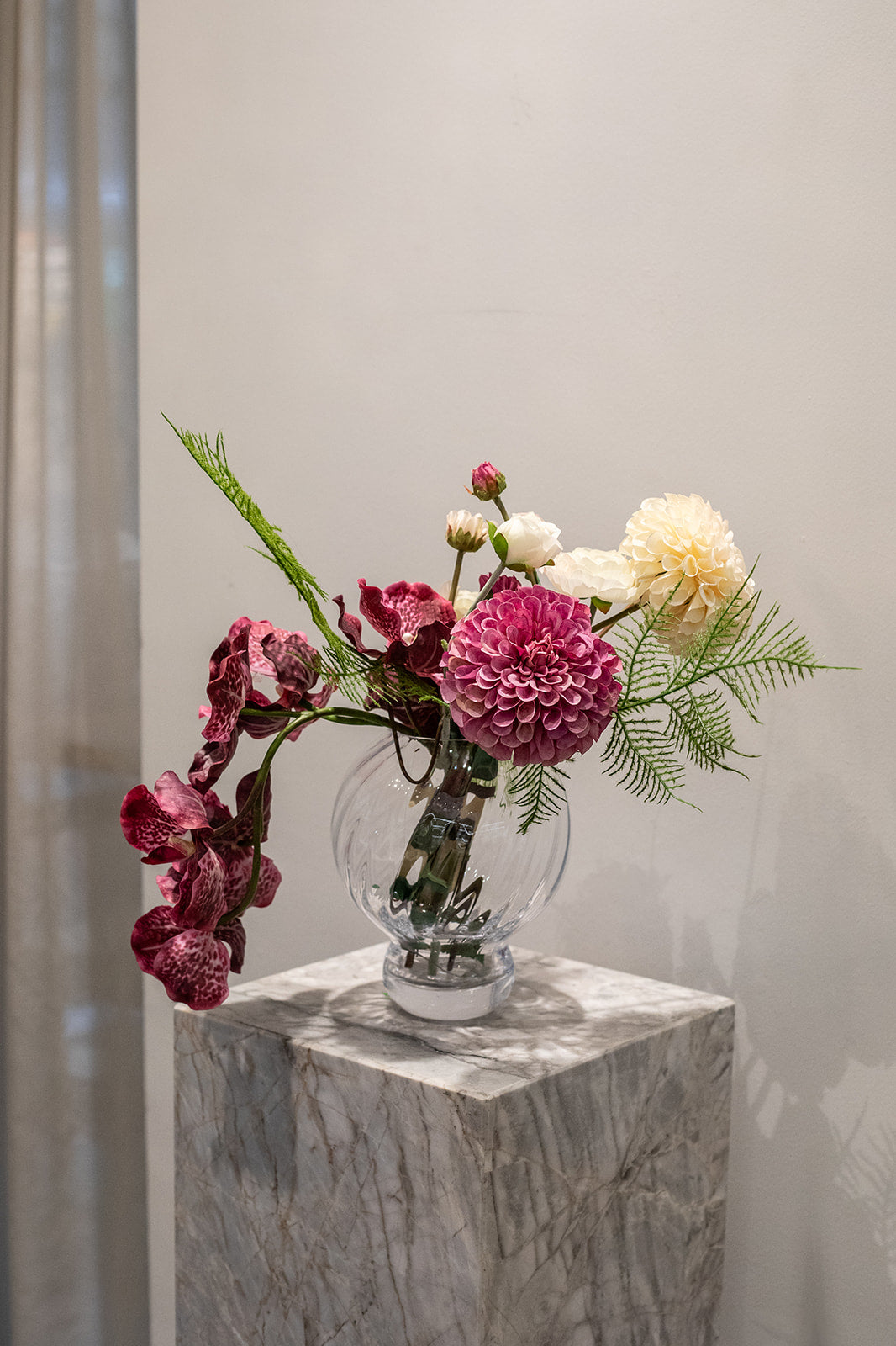Kunstig buket Stjernestrøet Flor med orkidé i blommefarve, cremefarvet og pink dahlia, hvid ranunkel og grøn bregne – naturtro og elegant.