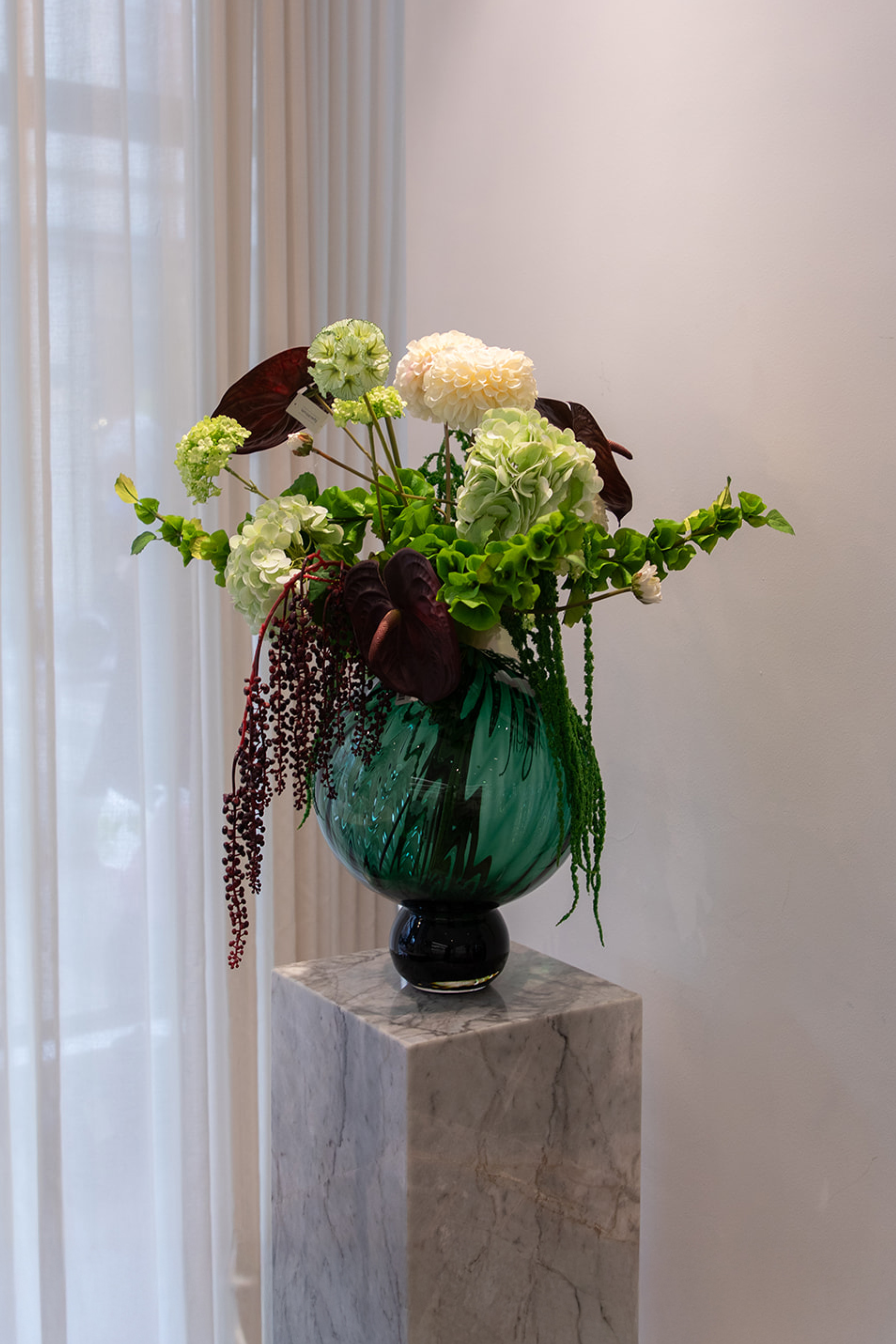 Kunstig buket i grønne og bordeaux nuancer med hortensia, cream dahlia, anthurium og bærgrene – fyldig og naturskøn i moderne stil.