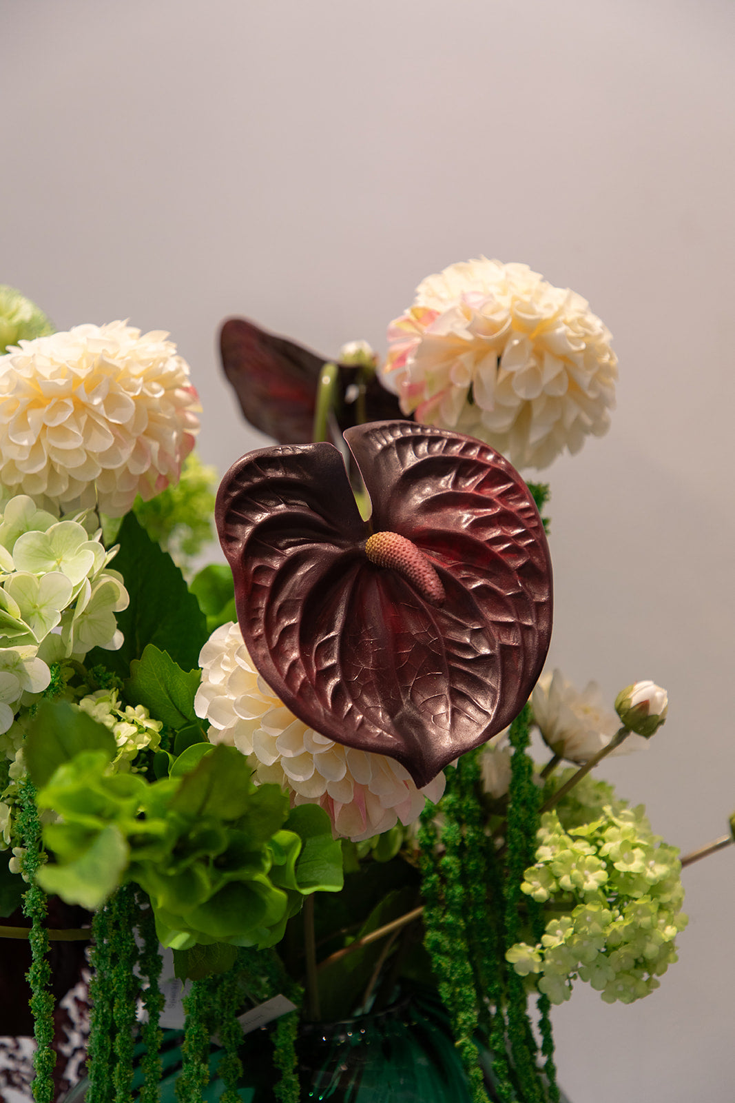 Kunstig buket i grønne og bordeaux nuancer med hortensia, cream dahlia, anthurium og bærgrene – fyldig og naturskøn i moderne stil.
